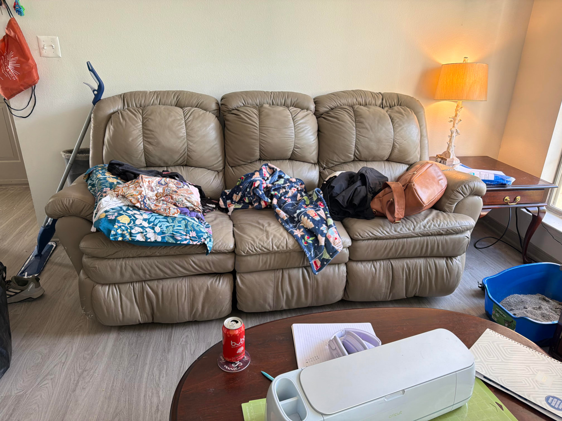 Living room in Granbury, TX before a home cleanout — couch piled with clothing and bags